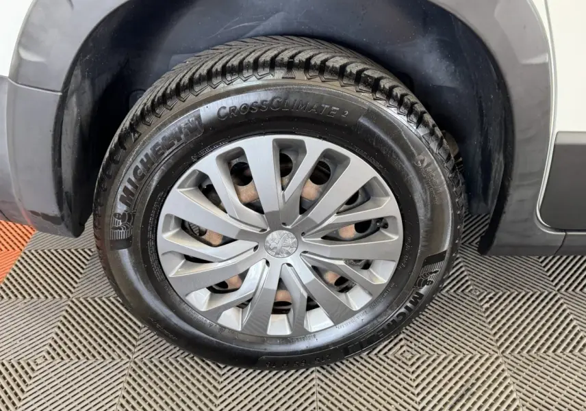 Gros plan sur la roue avant droite du Peugeot Rifter blanc, mettant en valeur la jante et le pneu Michelin CrossClimate 2.