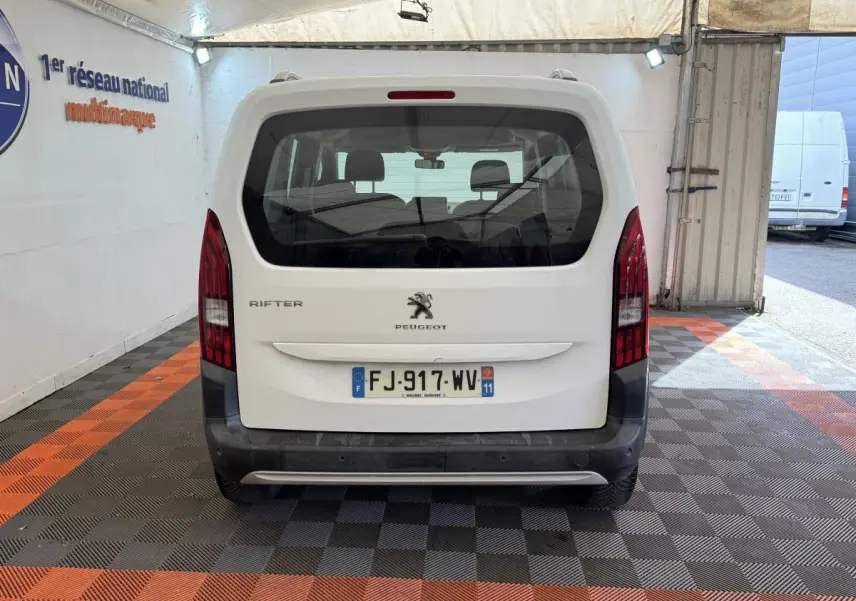 Vue arrière d'un Peugeot Rifter blanc 2019 avec feux verticaux rouges et plaque d'immatriculation française visible.