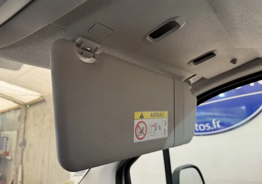 Détail intérieur du pare-soleil côté conducteur du Peugeot Rifter blanc, avec avertissement airbag visible.