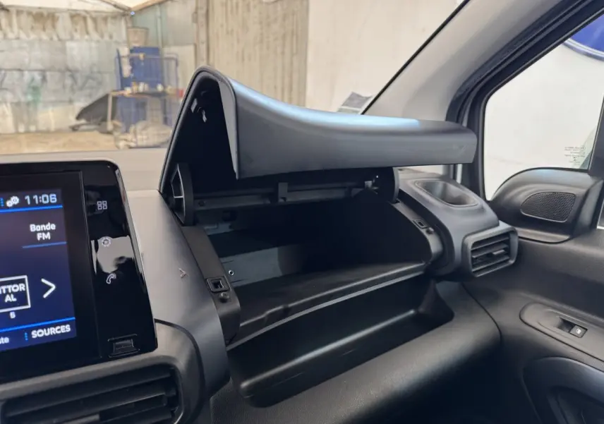 Intérieur du Peugeot Rifter blanc 2019, vue sur la boîte à gants ouverte côté passager et écran tactile du tableau de bord.
