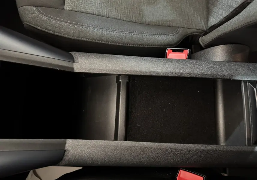 Vue rapprochée de la console centrale noire entre les sièges avant gris du Peugeot Rifter blanc 2019.