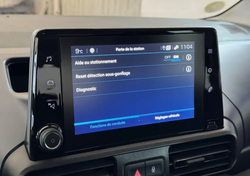 Écran tactile central du tableau de bord du Peugeot Rifter blanc, affichant les réglages d’aide au stationnement.