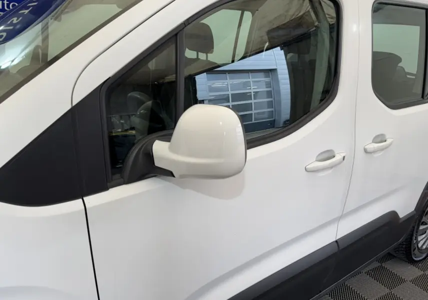 Vue latérale gauche du Peugeot Rifter blanc, mettant en valeur la porte arrière coulissante et le rétroviseur blanc.