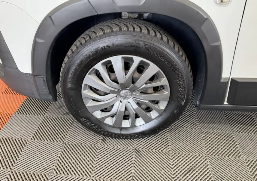 Gros plan sur la roue avant droite d’un Peugeot Rifter blanc, avec jante argentée et pneu hiver Hankook.