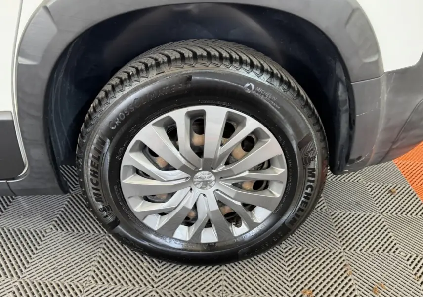 Gros plan sur la roue avant droite blanche du Peugeot Rifter 2019 avec jante argentée et pneu Michelin CrossClimate.