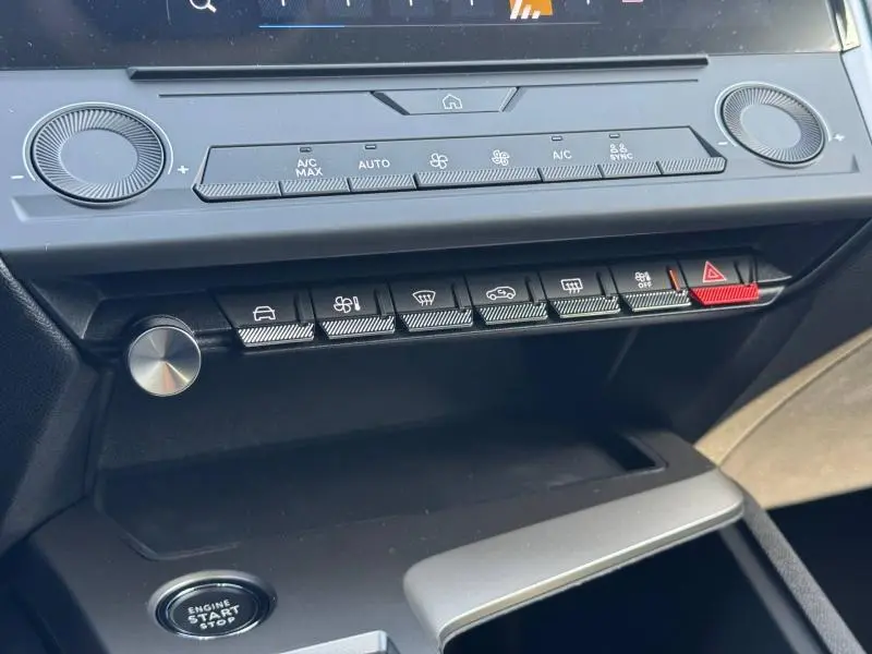 Vue rapprochée de la console centrale de la Peugeot 308 2025, boutons de climatisation et bouton rouge de danger visibles.