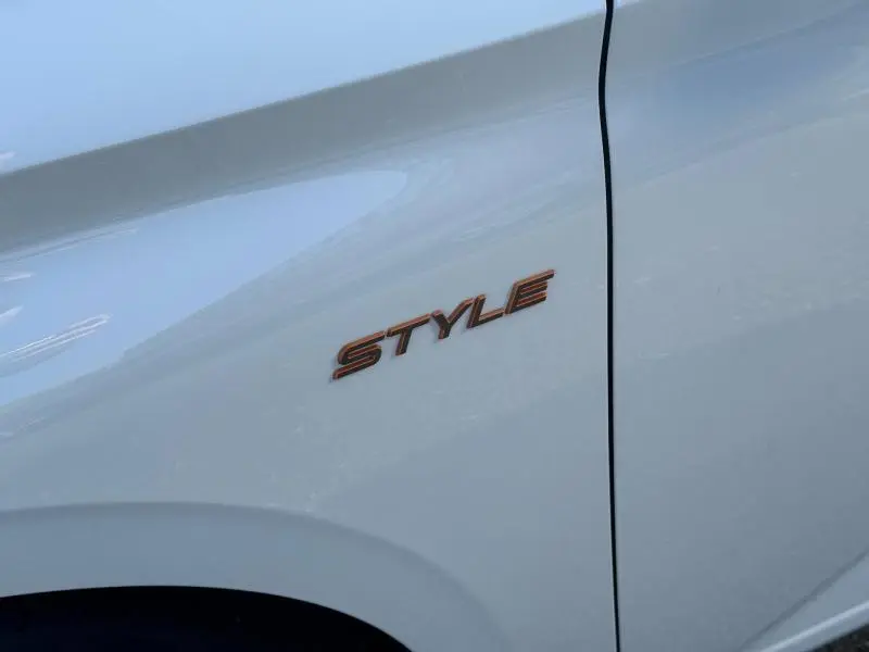 Gros plan sur l’inscription Style en relief couleur cuivre sur la portière blanche Okénite d’une Peugeot 308.