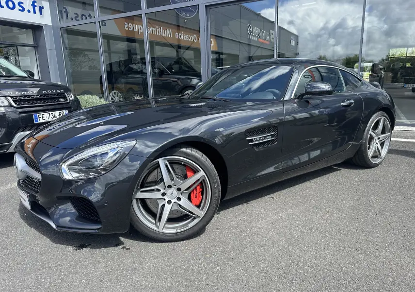 Mercedes AMG GT gris foncé vue en 3/4 avant droit, avec jantes cinq branches et étriers de frein rouges visibles.
