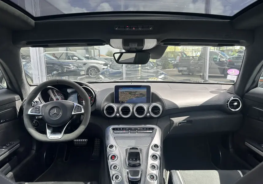 Intérieur de la Mercedes AMG GT 2015 en gris foncé, vue frontale du tableau de bord avec volant AMG et écran central.