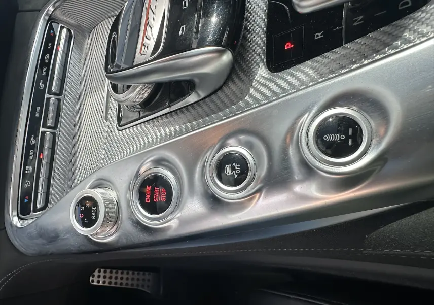 Gros plan sur la console centrale en aluminium brossé du Mercedes AMG GT 2015 avec levier de vitesse et boutons de contrôle.