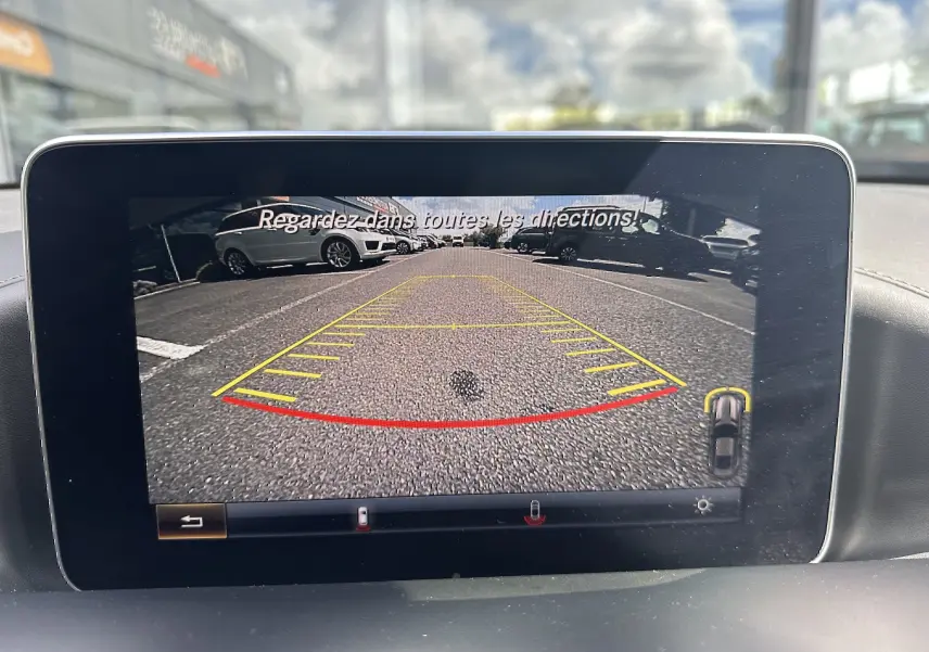 Vue de la caméra de recul du Mercedes AMG GT gris foncé, affichant le marquage au sol et les véhicules en arrière-plan.