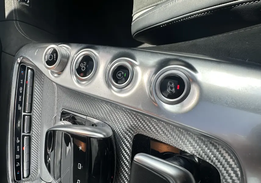 Détail de la console centrale en carbone et aluminium du Mercedes AMG GT 2015 avec commandes de climatisation et mode conduite.
