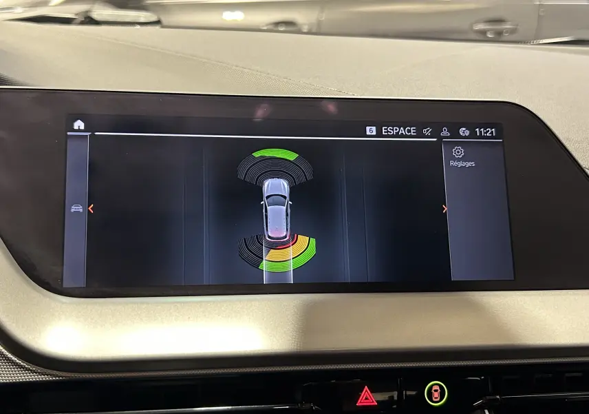 Écran central de BMW Série 1 16d 2023 affichant l'aide au stationnement avec capteurs avant et arrière en couleurs vives.