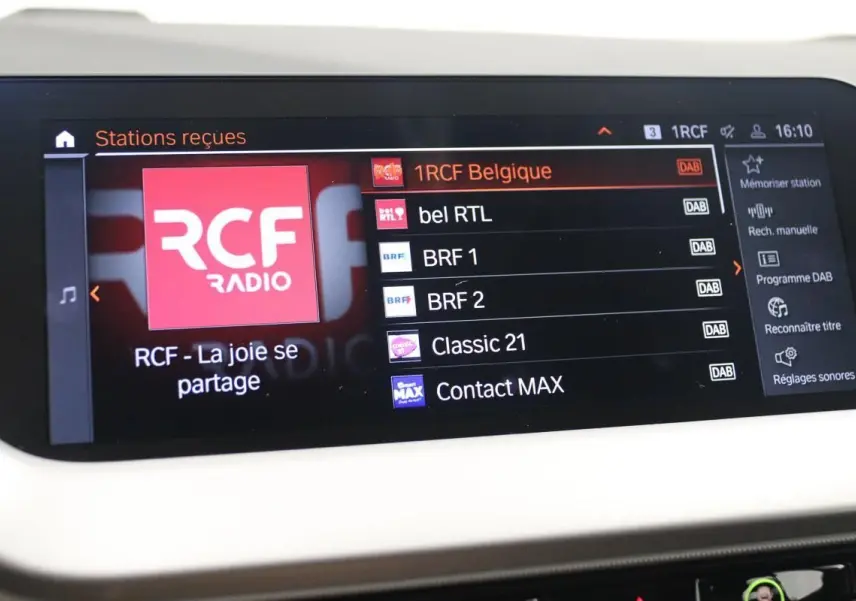 Écran tactile intérieur du système GPS de la BMW Série 1 16d 2023 affichant les stations radio numériques.