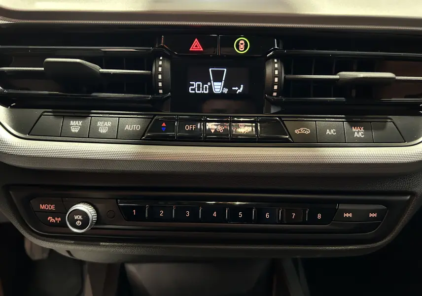 Tableau de bord de BMW Série 1 16d 2023 en gros plan, mettant en valeur la climatisation digitale et les commandes audio.