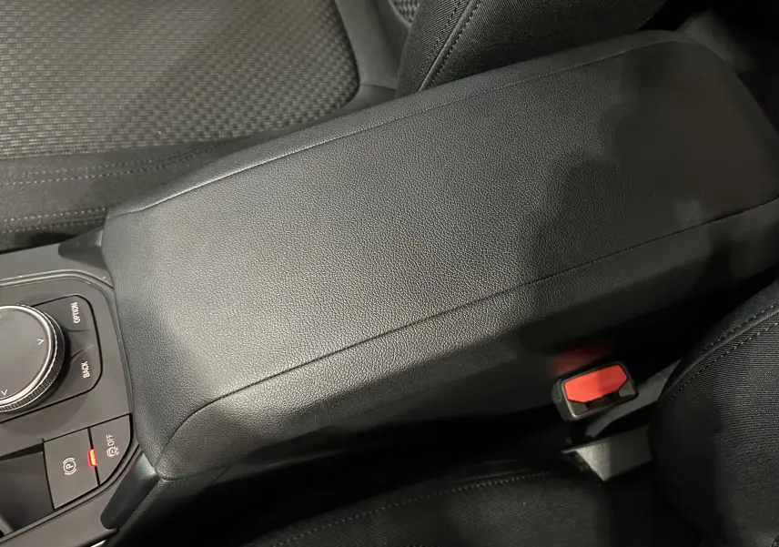 Accoudoir central noir en cuir avec commandes de la console et siège tissu dans une BMW Série 1 16d 2023.