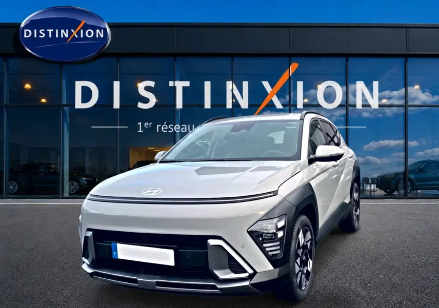Hyundai Kona hybride gris en 3/4 avant droit, avec jantes alliage et calandre épurée devant un showroom Distinxion.