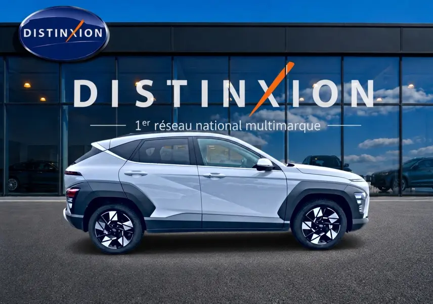 Vue latérale droite d'un Hyundai Kona gris 2025 avec protections noires et jantes alliage au design géométrique.