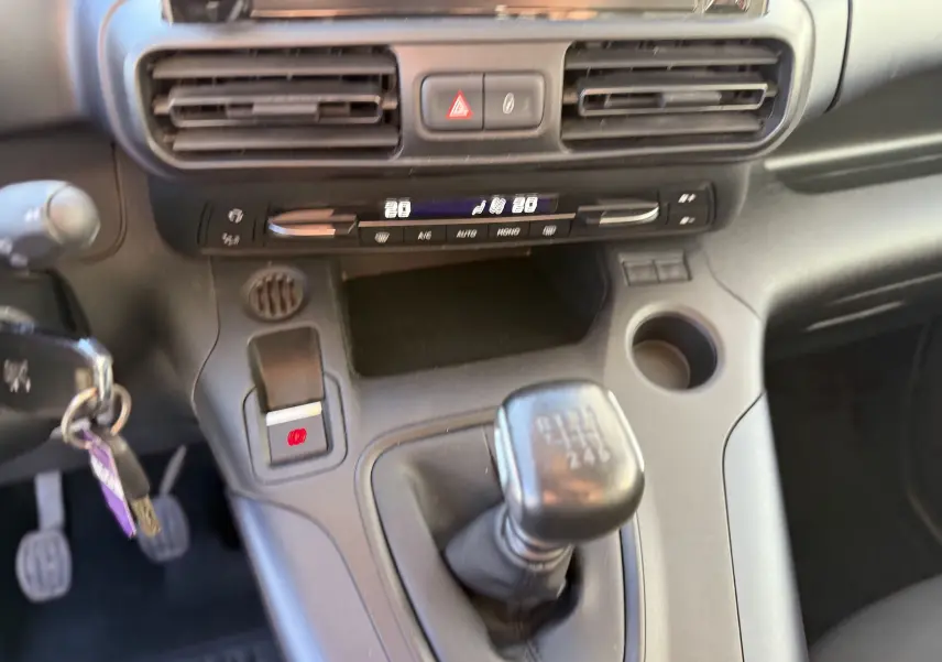 Vue intérieure centrée sur la console centrale grise du Peugeot Rifter 2020 avec levier de vitesse manuel et commandes climatisation.