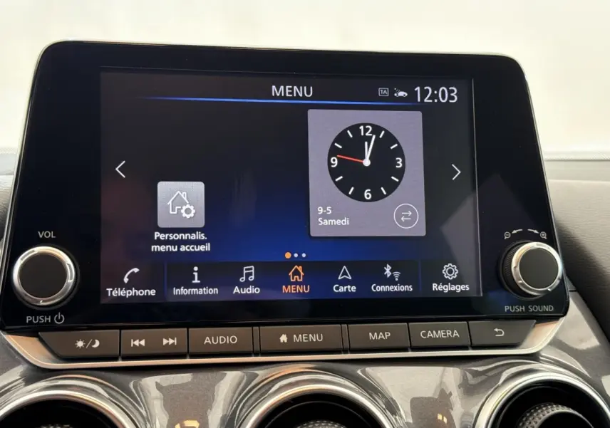 Écran tactile central du tableau de bord du Nissan Juke 2023, affichant l'horloge et le menu principal.