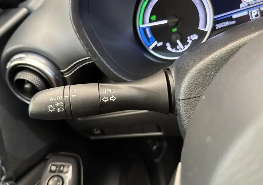 Gros plan sur la manette de clignotants et phares du tableau de bord d’un Nissan Juke gris foncé 2023.