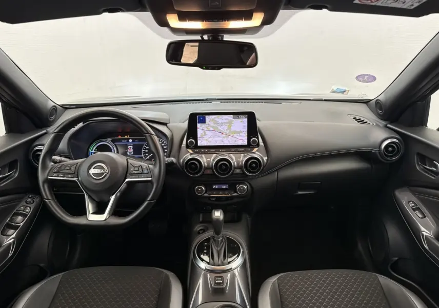 Vue intérieure avant du tableau de bord gris foncé du Nissan Juke 2023 avec écran tactile central et volant multifonctions.