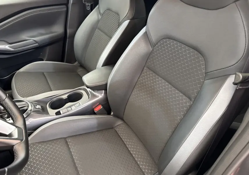 Vue intérieure rapprochée des sièges avant gris foncé du Nissan Juke 2023, avec console centrale et accoudoir visible.
