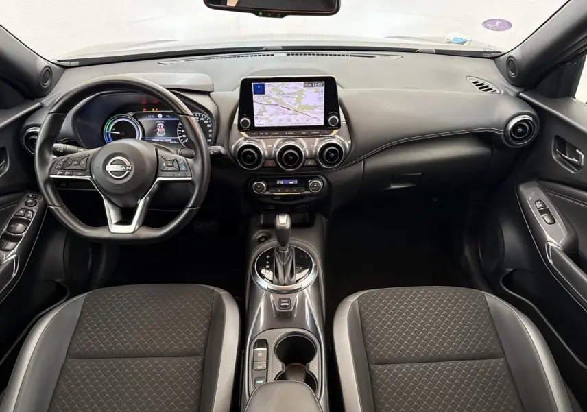 Intérieur avant du Nissan Juke 2023 gris foncé, vue centrée sur le tableau de bord avec écran tactile et volant multifonctions.