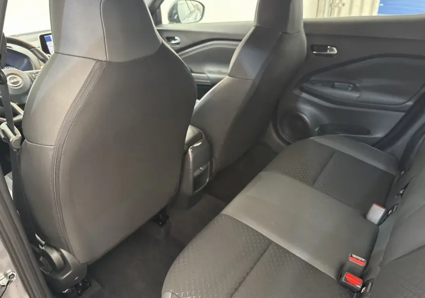 Vue intérieure arrière du Nissan Juke 2023 gris foncé, montrant la banquette 3 places et les dossiers des sièges avant en tissu noir.