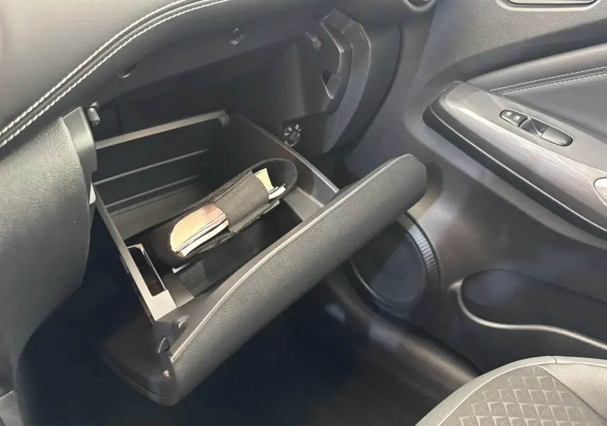 Vue intérieure côté passager du Nissan Juke 2023, boîte à gants ouverte avec rangement visible, sellerie noire.