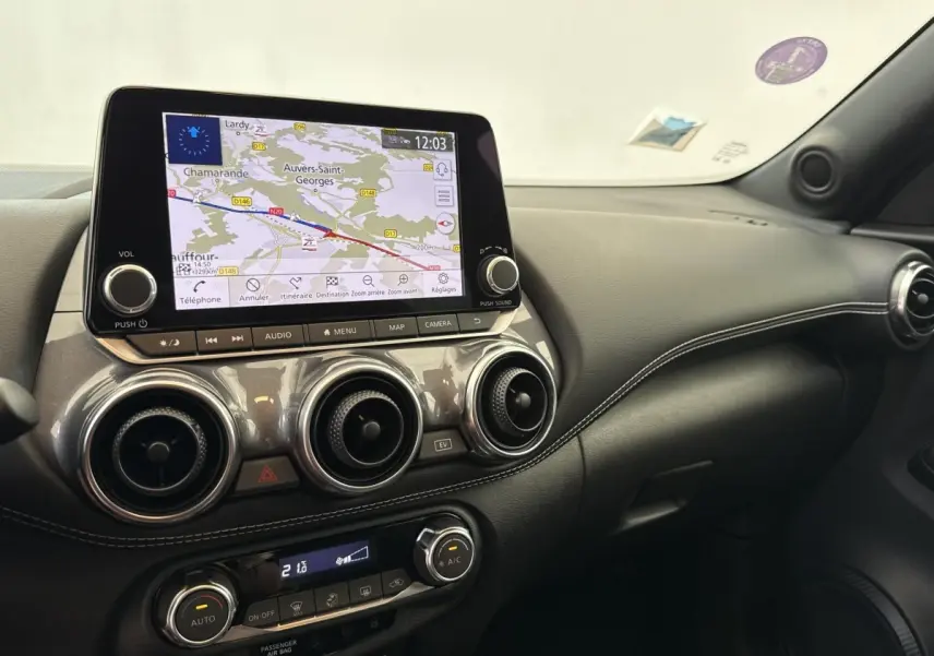 Vue intérieure du tableau de bord du Nissan Juke gris foncé 2023 avec écran tactile de navigation et aérateurs ronds.