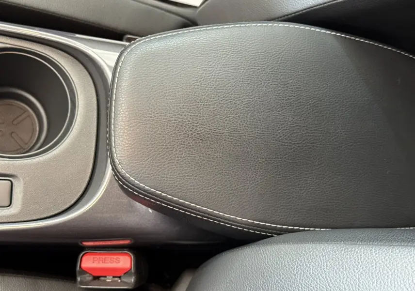 Détail de l'accoudoir central en cuir noir avec surpiqûres blanches dans l'habitacle du Nissan Juke 2023.