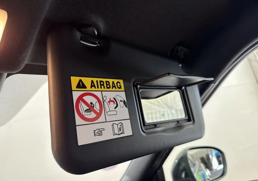 Détail du pare-soleil côté conducteur avec miroir et avertissement airbag dans un Nissan Juke gris foncé 2023.