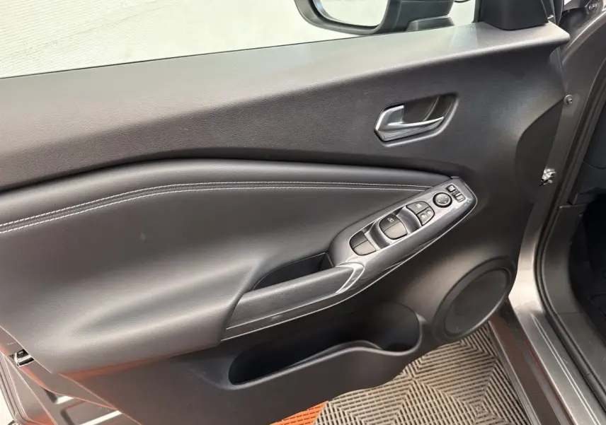 Vue intérieure côté conducteur de la porte gris foncé du Nissan Juke 2023 avec commandes électriques et haut-parleur intégré.