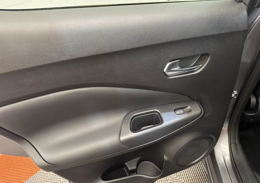 Vue rapprochée de la porte avant droite gris foncé du Nissan Juke 2023, avec poignée intérieure et commande de vitre.