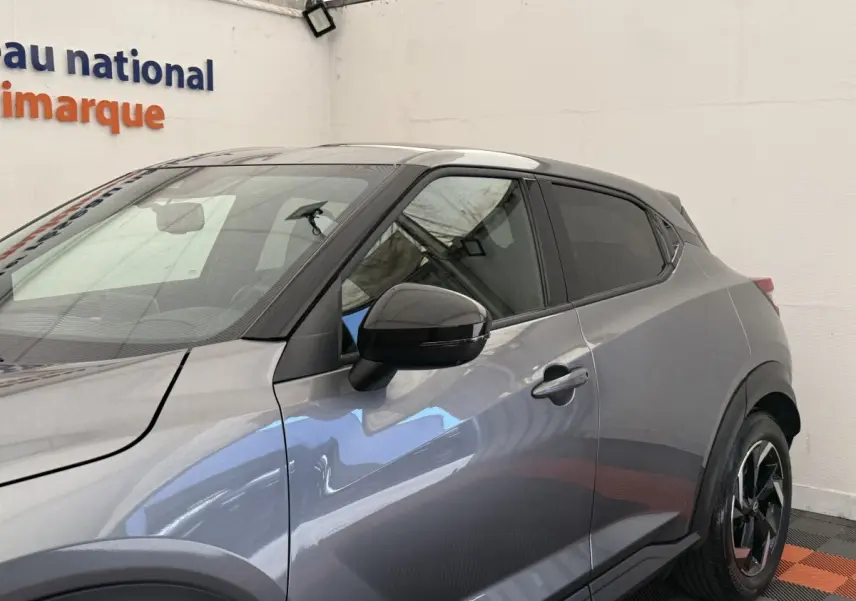 Vue de profil côté gauche du Nissan Juke 2023 gris foncé avec rétroviseur noir et jante alliage distinctive.