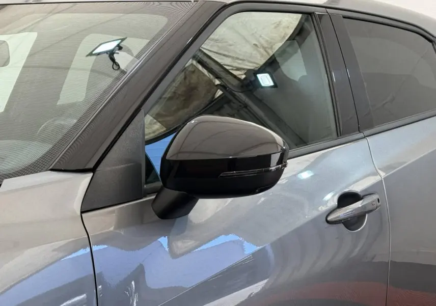 Gros plan sur le rétroviseur noir et la porte côté gauche d’un Nissan Juke gris foncé 2023.