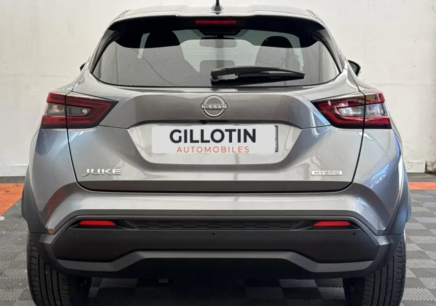 Vue arrière d'un Nissan Juke gris foncé 2023 hybride, avec feux LED et logo distinctif sur le hayon.