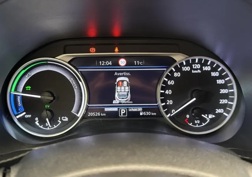 Vue rapprochée du tableau de bord numérique du Nissan Juke 2023, affichant la vitesse, autonomie et avertissements.