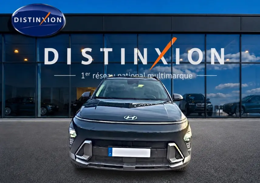 Vue frontale d'une Hyundai Kona 2025 gris ecotronic devant une vitrine Distinxion, avec feux LED et calandre moderne.