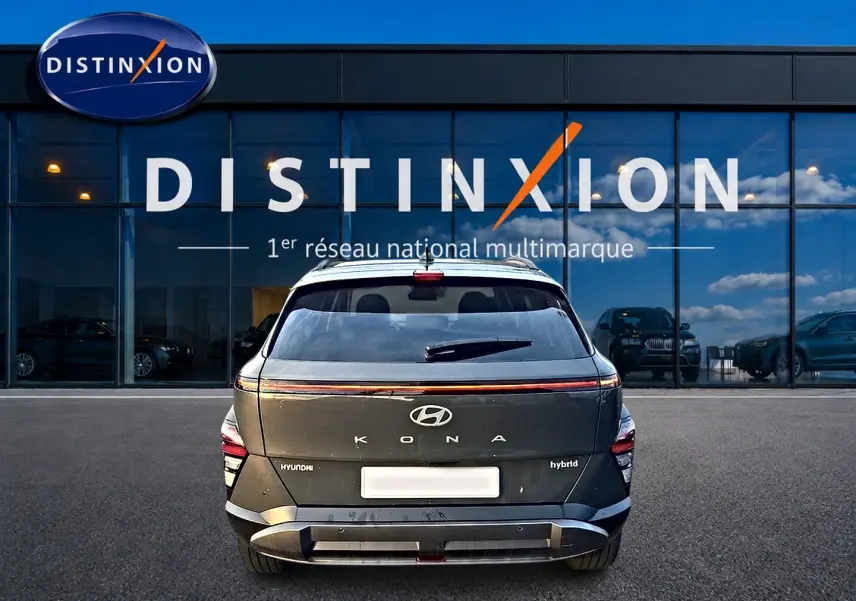 Vue arrière d’un Hyundai Kona hybride gris ecotronic, avec feux LED et logo Hyundai visible devant un showroom Distinxion.