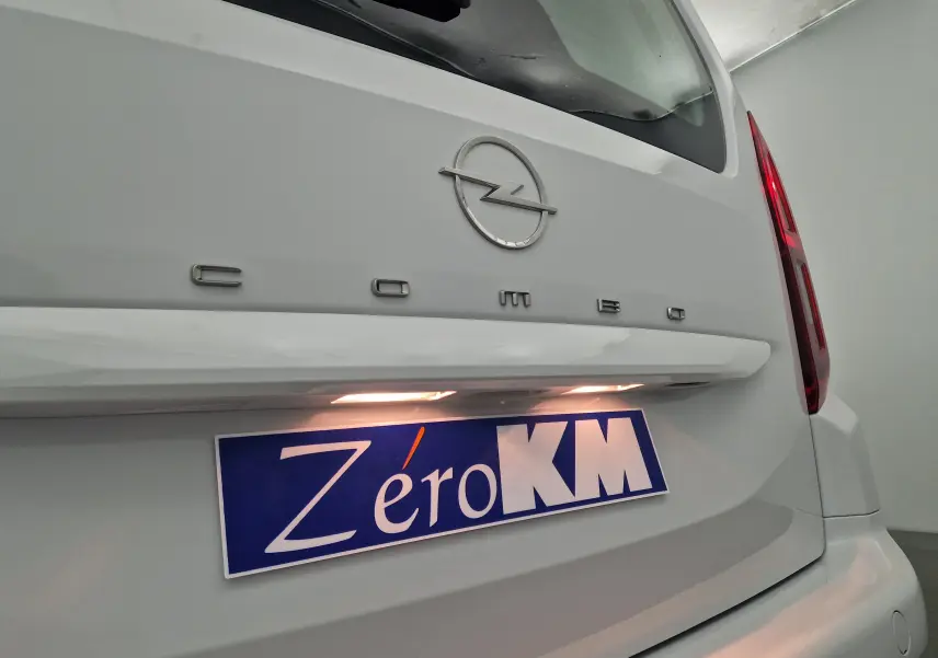 Gros plan sur l'arrière blanc d'un Opel Combo Life avec logo et plaque d'immatriculation Zéro KM éclairée.