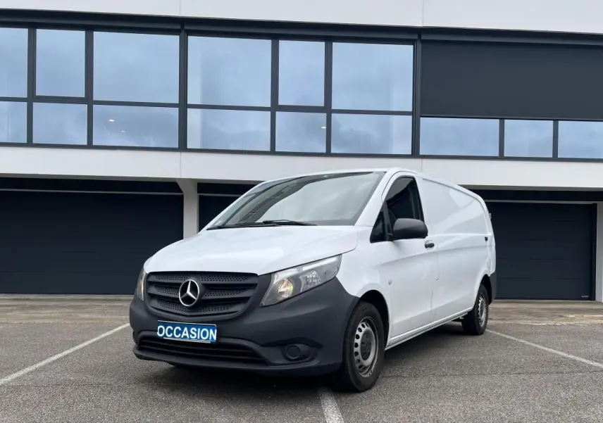 Vue 3/4 avant droit d’un Mercedes Vito Fourgon blanc avec pare-chocs noir et plaque "OCCASION" sur parking.