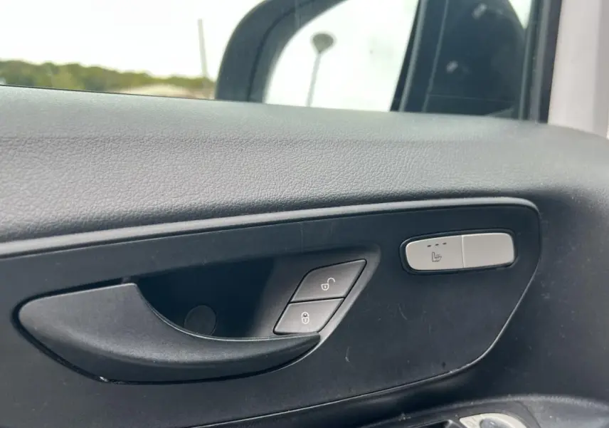 Gros plan sur la poignée intérieure côté gauche du Mercedes Vito Fourgon blanc avec bouton de siège chauffant visible.