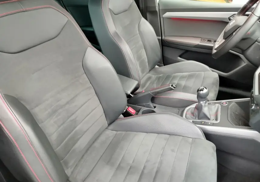 Vue intérieure côté conducteur et passager avant d'une SEAT Arona 2020, sièges en cuir et alcantara gris avec surpiqûres rouges.