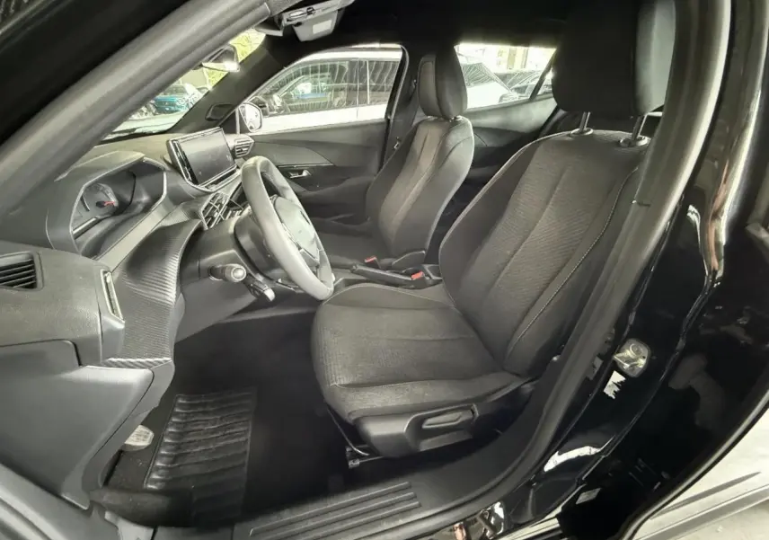 Intérieur du Peugeot 2008 2025 noir perla nera, vue côté conducteur, sièges tissu et tableau de bord moderne.