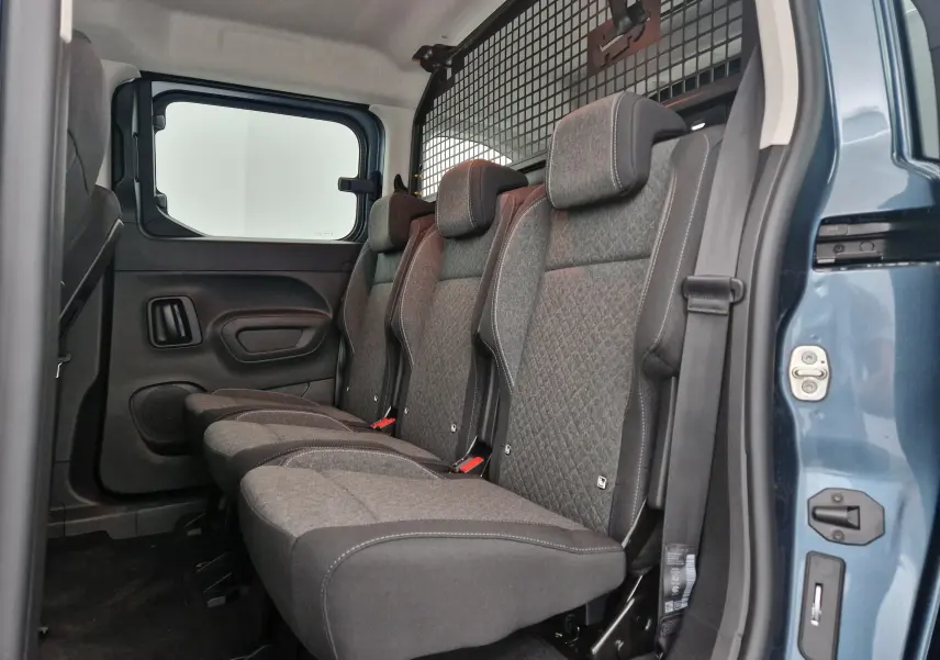 Vue latérale droite des trois sièges individuels arrière gris foncé de l'Opel Combo Life Bleu Kiama avec grille de séparation.