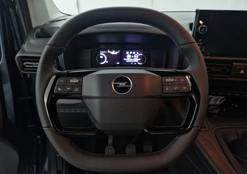 Vue rapprochée du volant cuir noir de l'Opel Combo Life 2025 avec commandes intégrées et tableau de bord numérique.