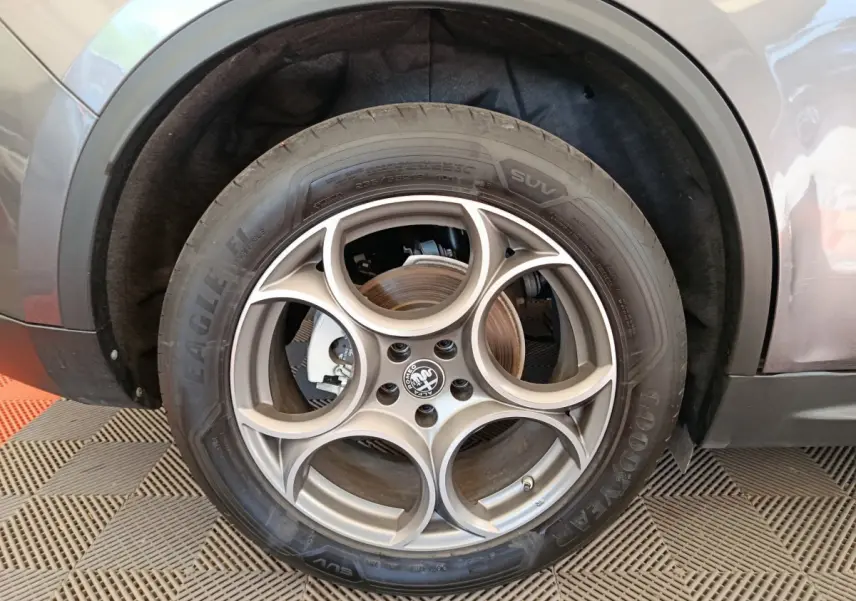 Gros plan sur la roue avant gauche gris foncé d'un Alfa Romeo Stelvio 2024 avec jante en alliage à cinq cercles.