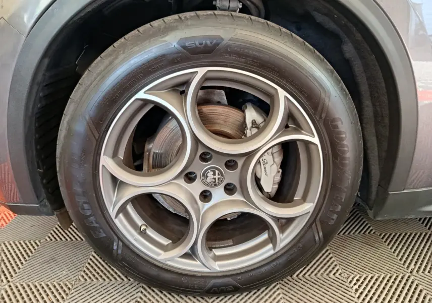 Gros plan sur la roue avant droite gris foncé d'un Alfa Romeo Stelvio 2.2 TD 160 AT8 Sprint avec jante en alliage distinctive.